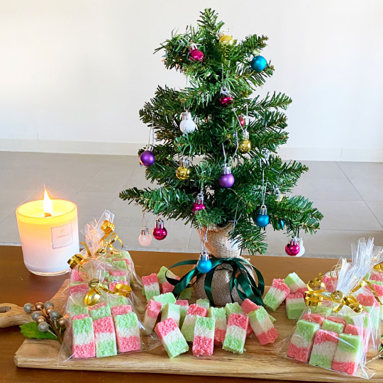 YourKitchen with Trudi: Coconut Ice on wooden food platter, surrounded by a Christmas Tree and a lit candle
